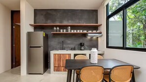 Een moderne keuken met een geïntegreerde koelkast, houten kastjes en een eethoek met rieten stoelen.