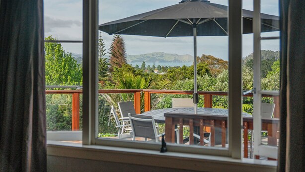 Ein Balkon mit Tisch, Stühlen und Sonnenschirm, mit Blick auf die Landschaft.