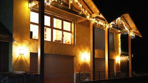 Ein Gebäude mit mehreren Fenstern, einige mit Vorhängen, und Lichterketten entlang des Daches.