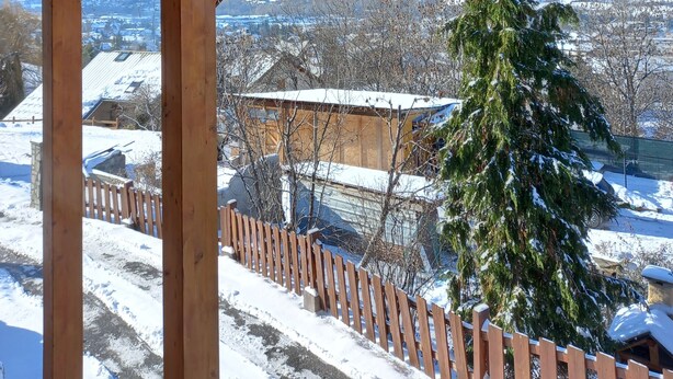 Eine Holzhütte mit Blick auf eine verschneite Landschaft und einen Baum.