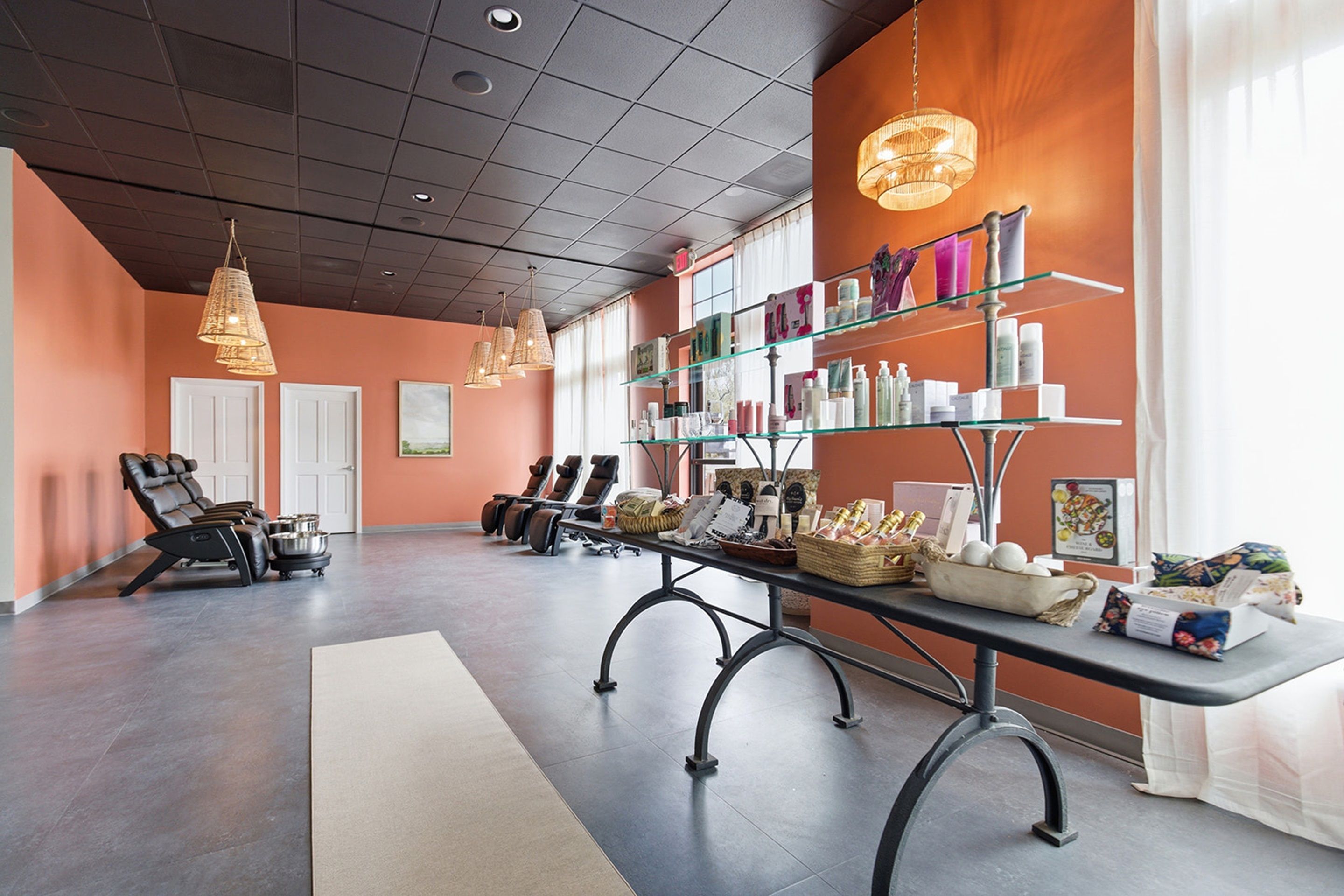 Un salón de spa con sillones de masaje, una recepción y estanterías con productos.