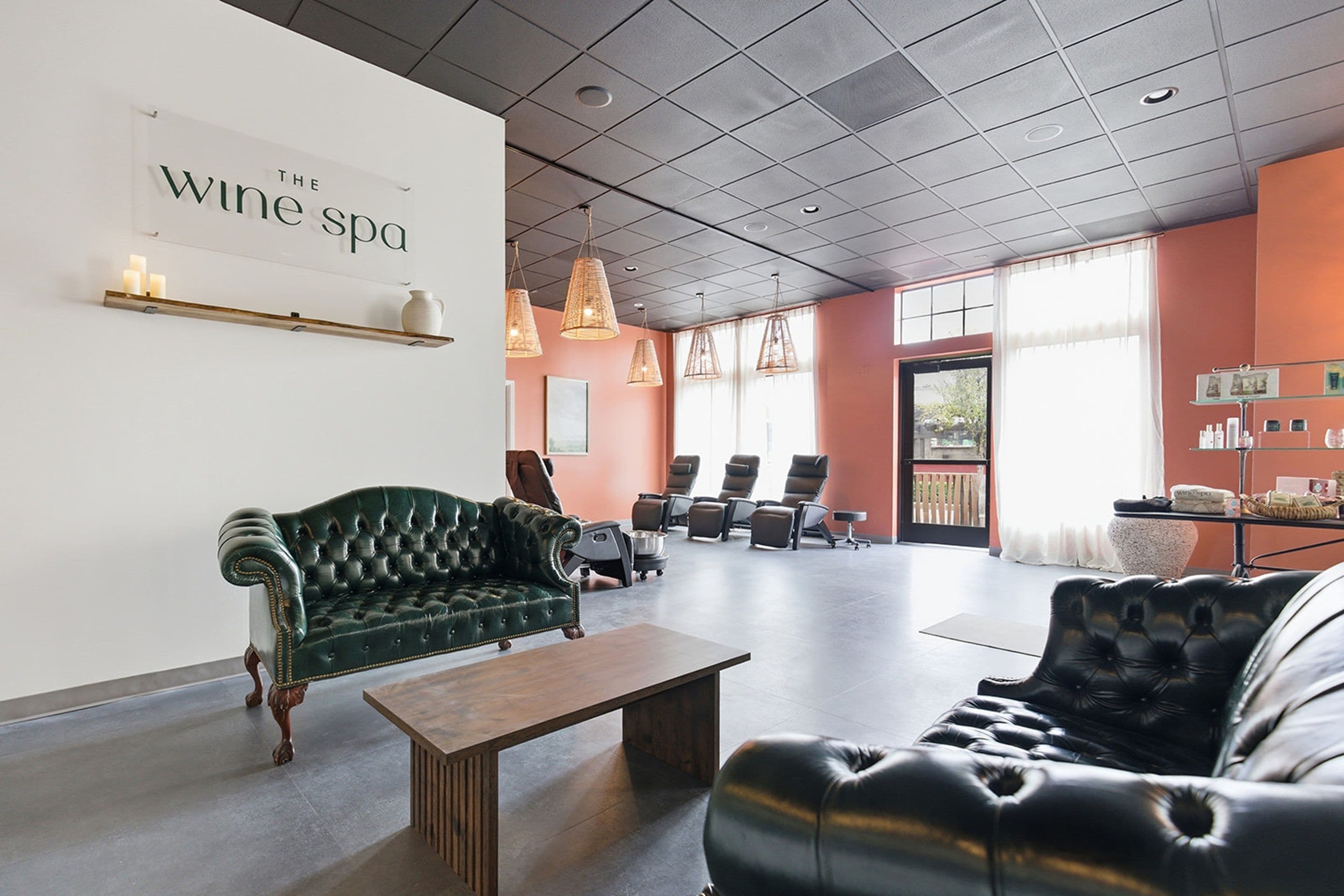 A spacious lounge area with a green sofa, a black leather couch, and a wooden coffee table.