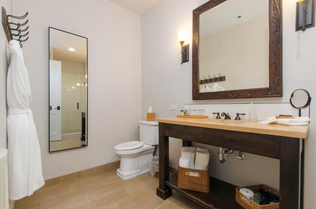 A bathroom with a wooden vanity, a large mirror, a towel rack, and a toilet.