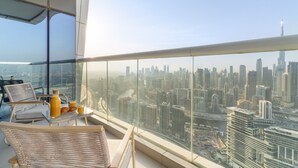 Ein Balkon mit Blick auf die Stadt, ein Tisch mit Frühstücksangeboten und ein Korbstuhl.