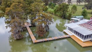 A lakeside property with a wooden dock extending into the water, surrounded by trees.