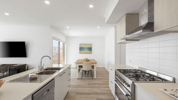 Een moderne keuken met een centraal eiland, een eetgedeelte met uitzicht, en een aan de muur bevestigde televisie.