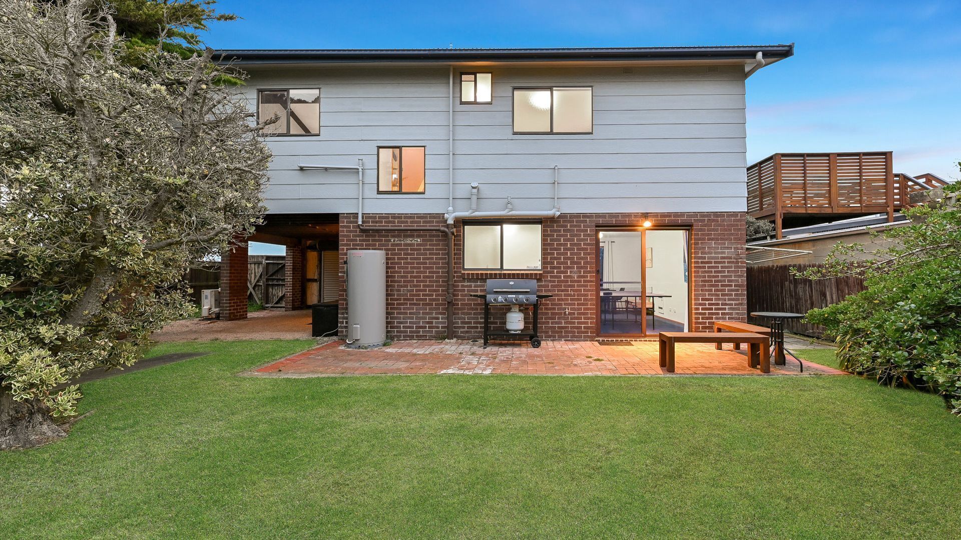 A two-story house with a backyard patio, a barbecue grill, and a covered outdoor seating area.