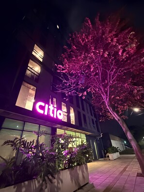 A building with a 'Citi' sign, large windows, and potted plants in front. - CITIO Hotel - Laureles (Medellín)