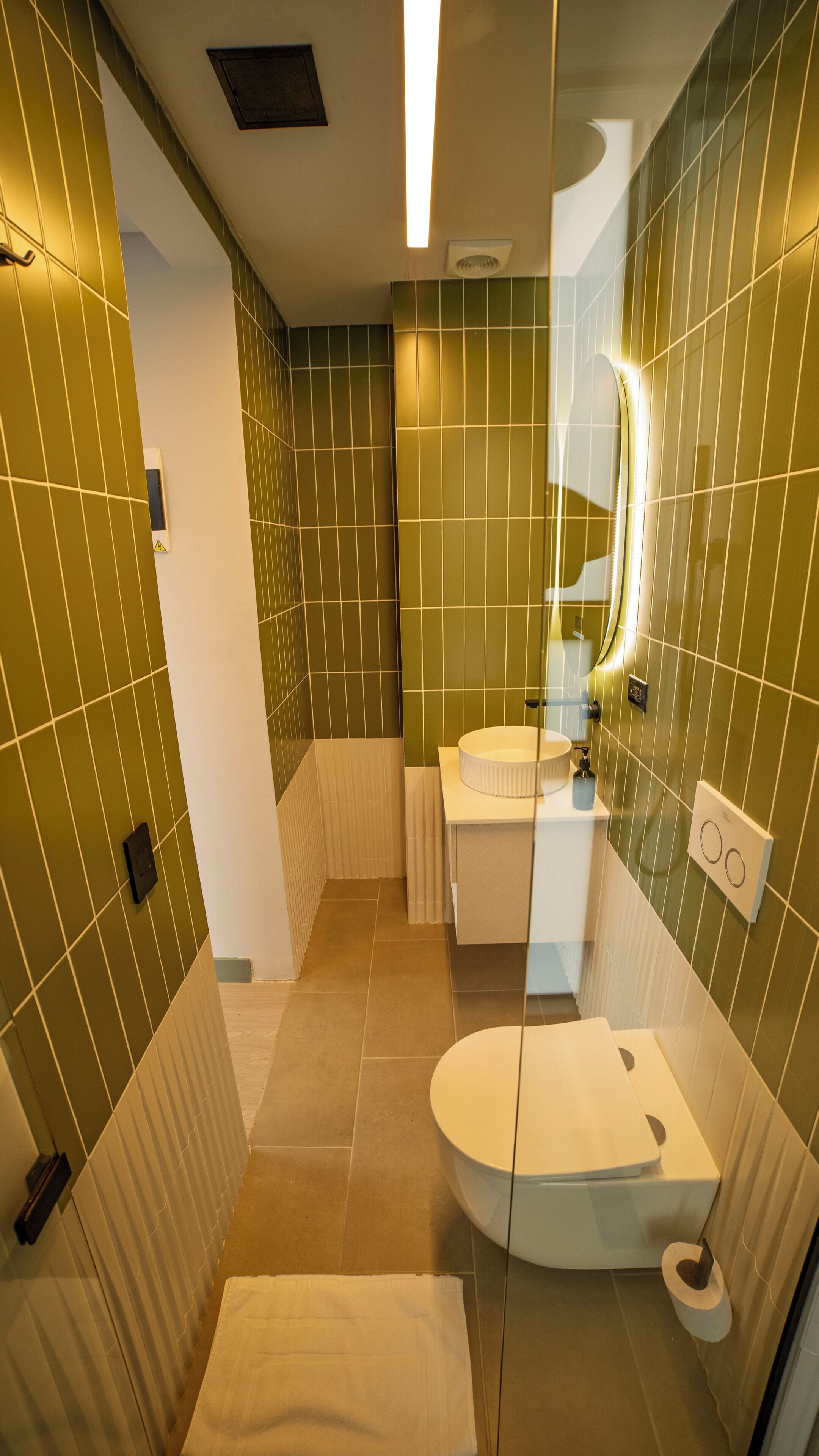 Un baño moderno con inodoro, lavamanos y espejo.