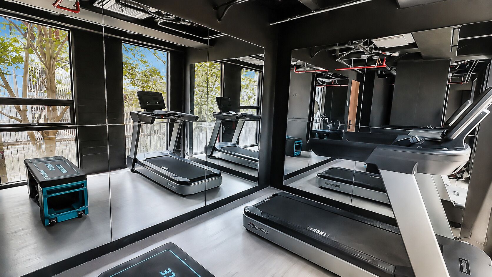 A modern gym with multiple treadmills, a rowing machine, and a small blue exercise bike.