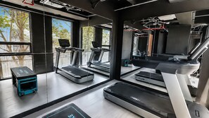 A modern gym with multiple treadmills, a rowing machine, and a small blue exercise bike.