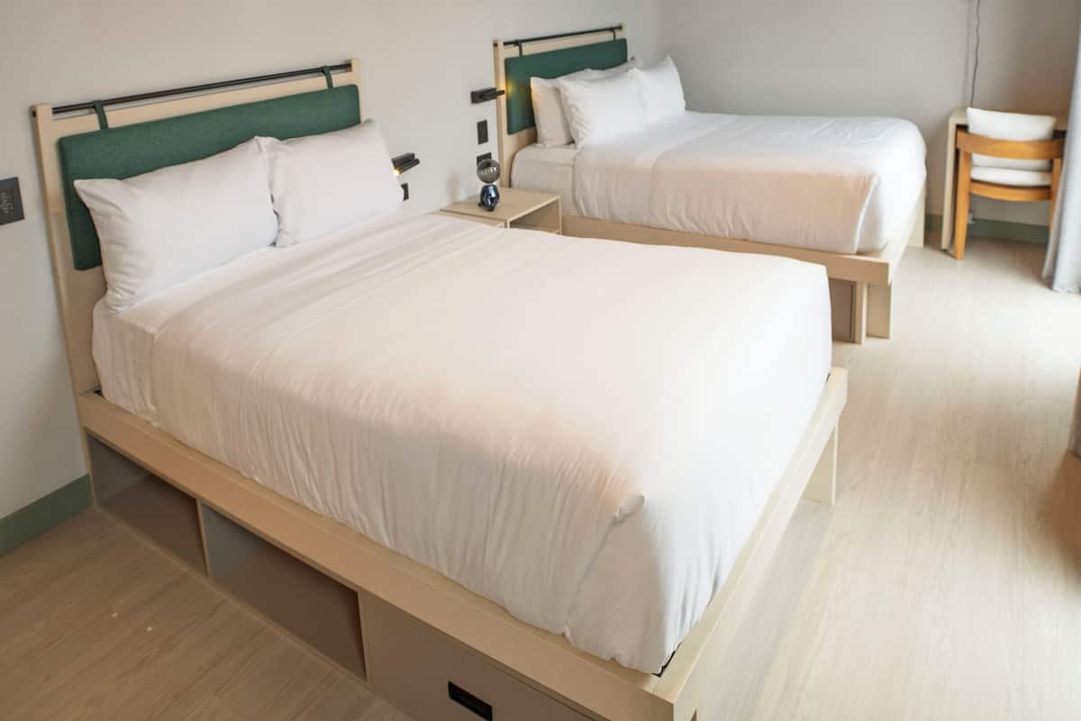 A hotel room with two beds, a TV, and a desk.