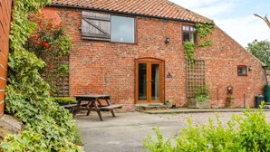 A brick building with a tiled roof, a wooden door, and a picnic table outside. - Barn Owl (Louth)