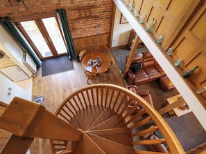 A spiral staircase, a dining area with a round table and chairs, and a leather sofa. - Barn Owl (Louth)
