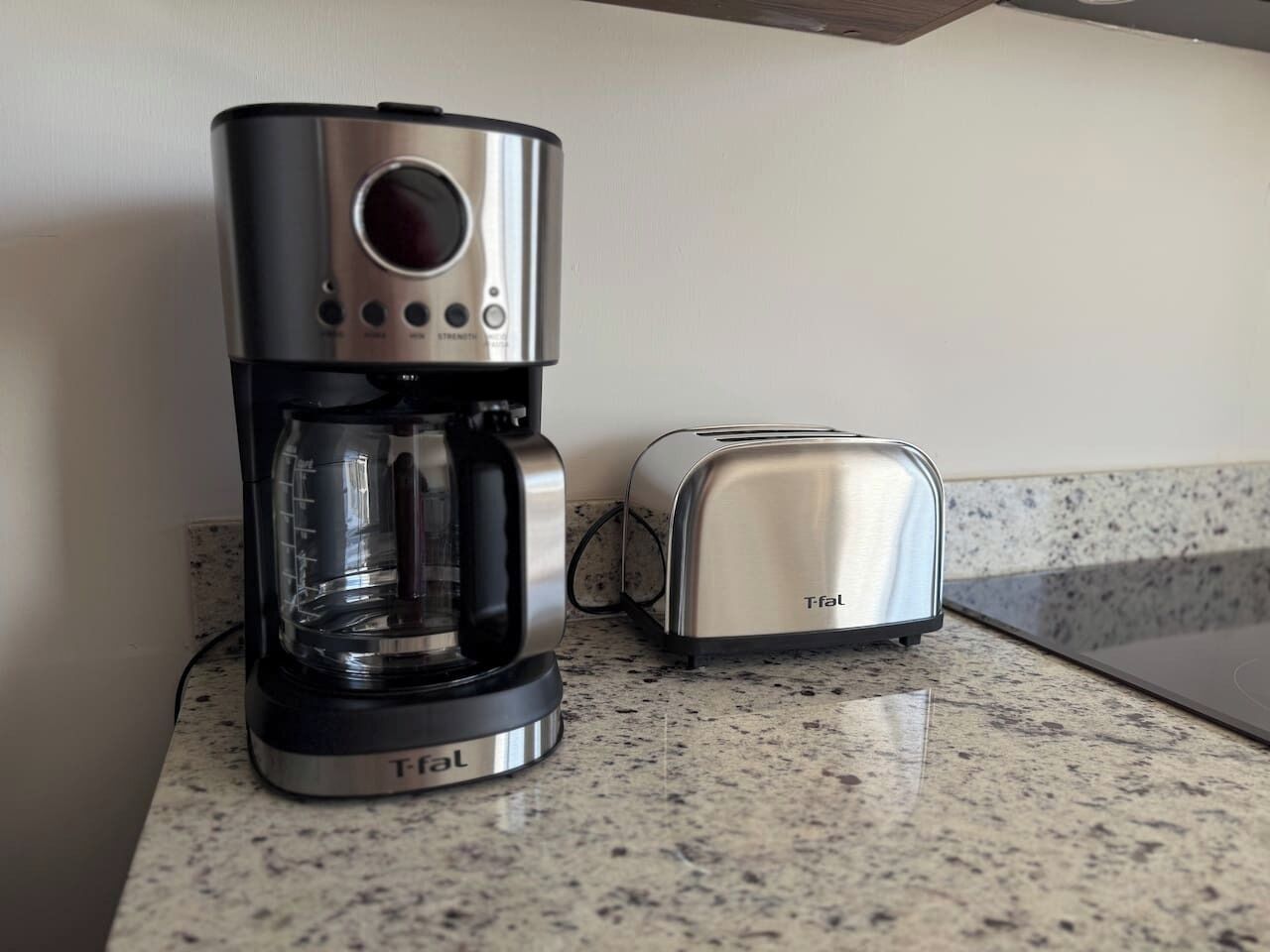 Une machine à café et un grille-pain de la marque Tefal sont posés sur un plan de travail de cuisine.