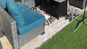 An outdoor patio area with a large sectional sofa, a small table, and a flat-screen TV mounted on the wall. - Spacious 4-bedroom house, perfect for entertaining in the heart of Ridgecrest. (Ridgecrest)