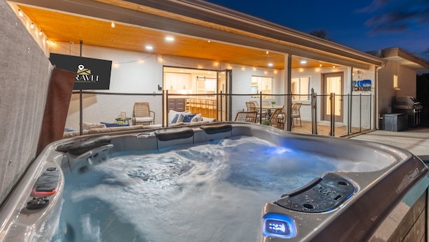 Un bain à remous doté d’un panneau de commande, une pergola en bois et un bâtiment sur lequel est apposée une enseigne indiquant « RAVLI ».