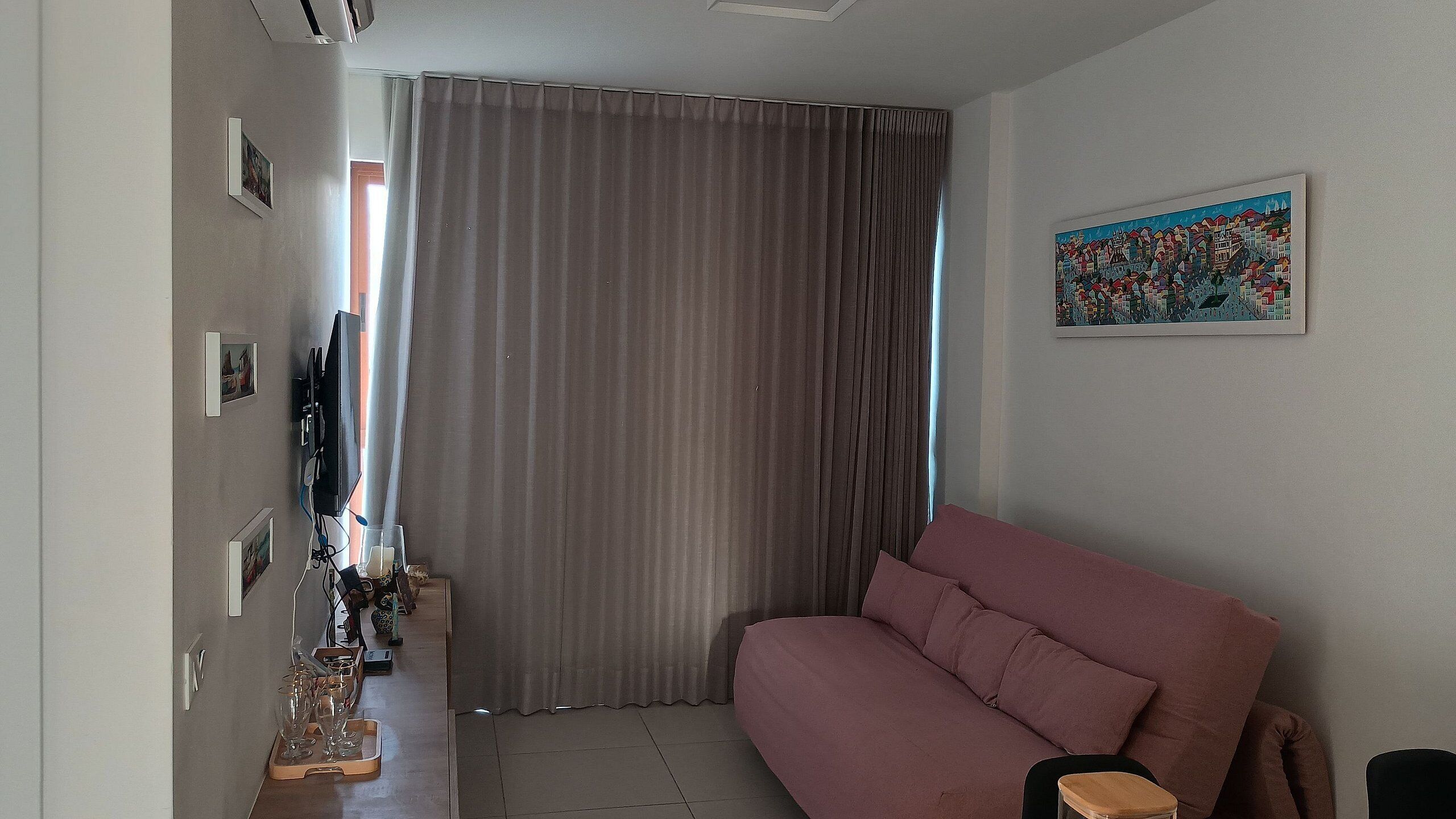 Een woonkamer met een bank, een televisie en een schilderij aan de muur.