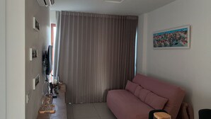 A living room with a sofa, a TV, and a painting on the wall. - Cozy Apt Sea View Barra - Nau0810 (Salvador)