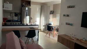A modern kitchen with a refrigerator, stove, and coffee machine. There is a dining area with a table and chairs. - Cozy Apt Sea View Barra - Nau0810 (Salvador)