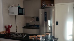 A modern kitchen with a stainless steel refrigerator, a microwave, and a gas stove. There are jars with lids on the counter. - Cozy Apt Sea View Barra - Nau0810 (Salvador)
