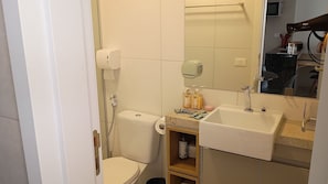 A compact bathroom with a toilet, a sink, and a mirror. - Cozy Apt Sea View Barra - Nau0810 (Salvador)