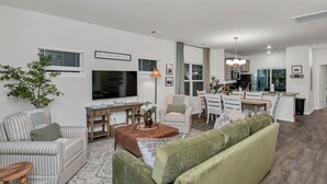 Uma sala de estar moderna com TV, sofá e área de jantar.