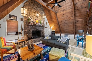 Un acogedor loft con chimenea de piedra, vigas de madera y una alfombra colorida.