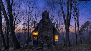 A stone cabin with a chimney, two lit windows, and a door. - A-Frame w/ VIEWS | Walk to Downtown/Park | Pets OK (Mentone)