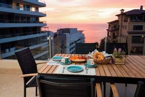 A table set for breakfast with a view of the sea, overlooking modern buildings. - Steps to Medano Beach | 3BR Condo Sleeps 8 (El Medano Beach)