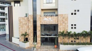A modern building with a stone facade, a glass entrance, and a logo above the doors. - Steps to Medano Beach | 3BR Condo Sleeps 8 (El Medano Beach)