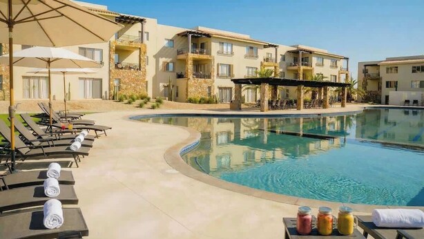 Un espace aménagé au bord de la piscine, avec des chaises longues, des parasols et une piscine.