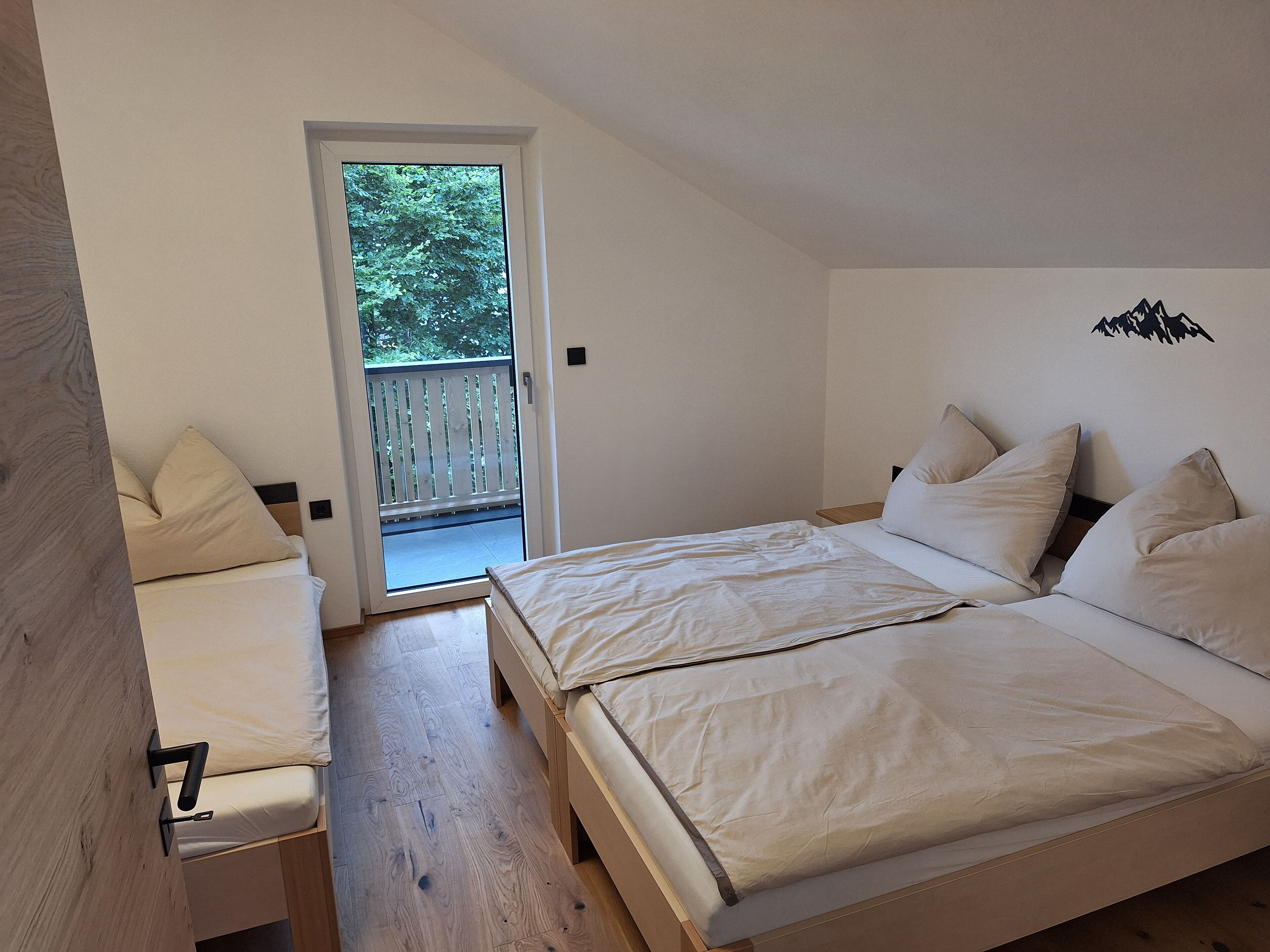 A bedroom with a bed, a bench, and a door leading to a balcony.