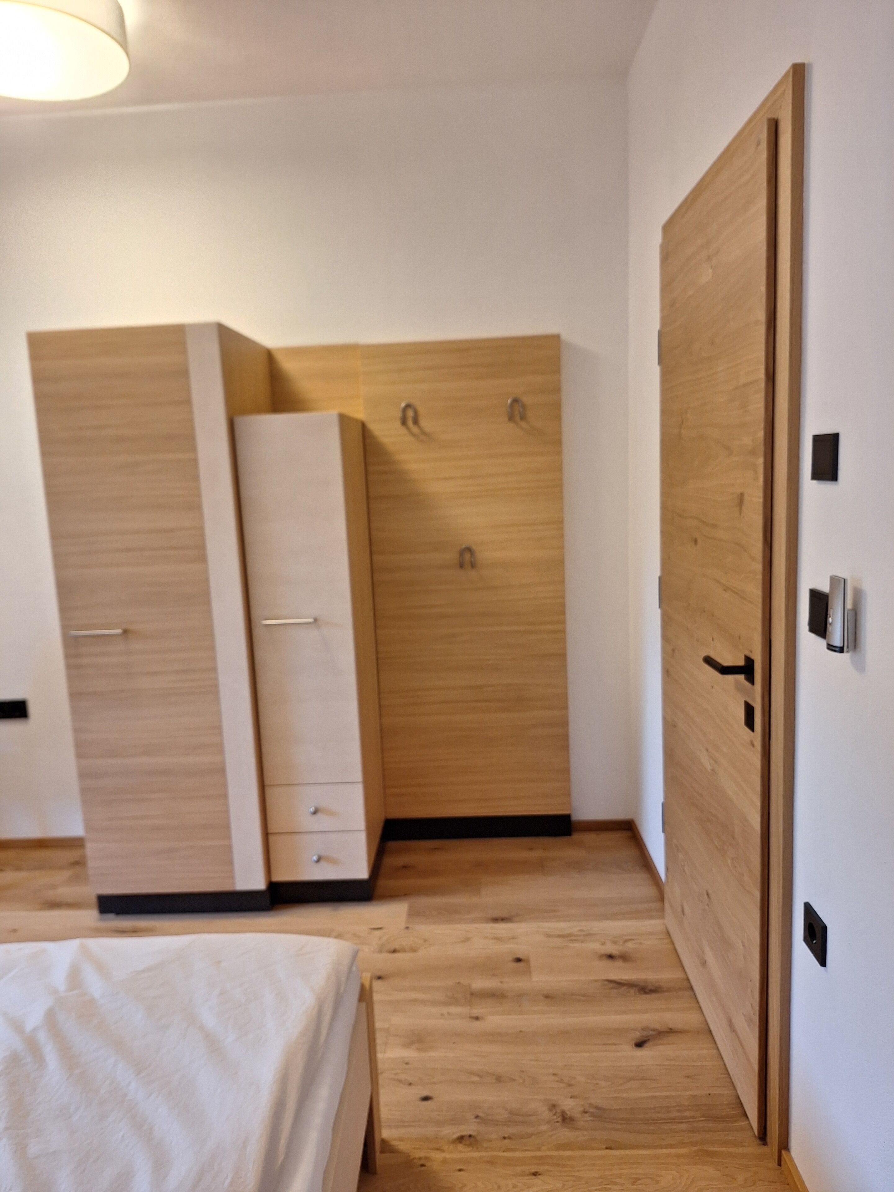 Een slaapkamer met een bed, een kledingkast en een deur.