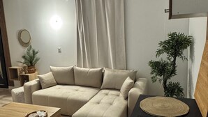 Una sala de estar moderna con un sofá beige, una mesa de centro de madera y una mesita auxiliar negra.