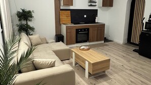 Una sala de estar moderna con un sofá, una mesita de centro y una cocina con armarios y un televisor.