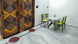 Une pièce avec une porte en bois, une petite table avec des chaises et une bouteille d’eau posée sur la table.