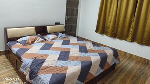 Une chambre à coucher avec un lit en bois, une courtepointe, une fenêtre avec des rideaux et une porte.
