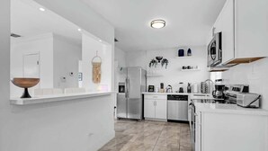 Uma cozinha moderna com armários brancos, eletrodomésticos de aço inoxidável e uma ilha central.