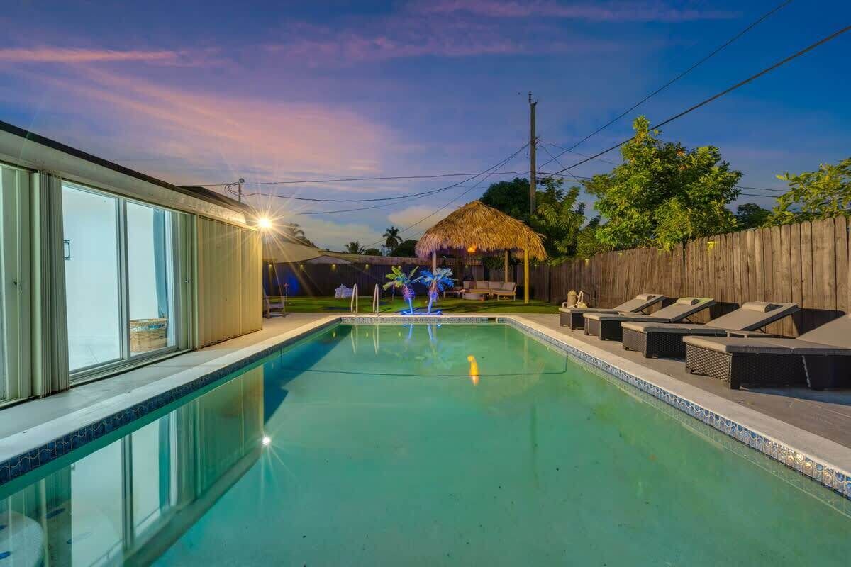 A swimming pool with lounge chairs and a thatched-roof structure.