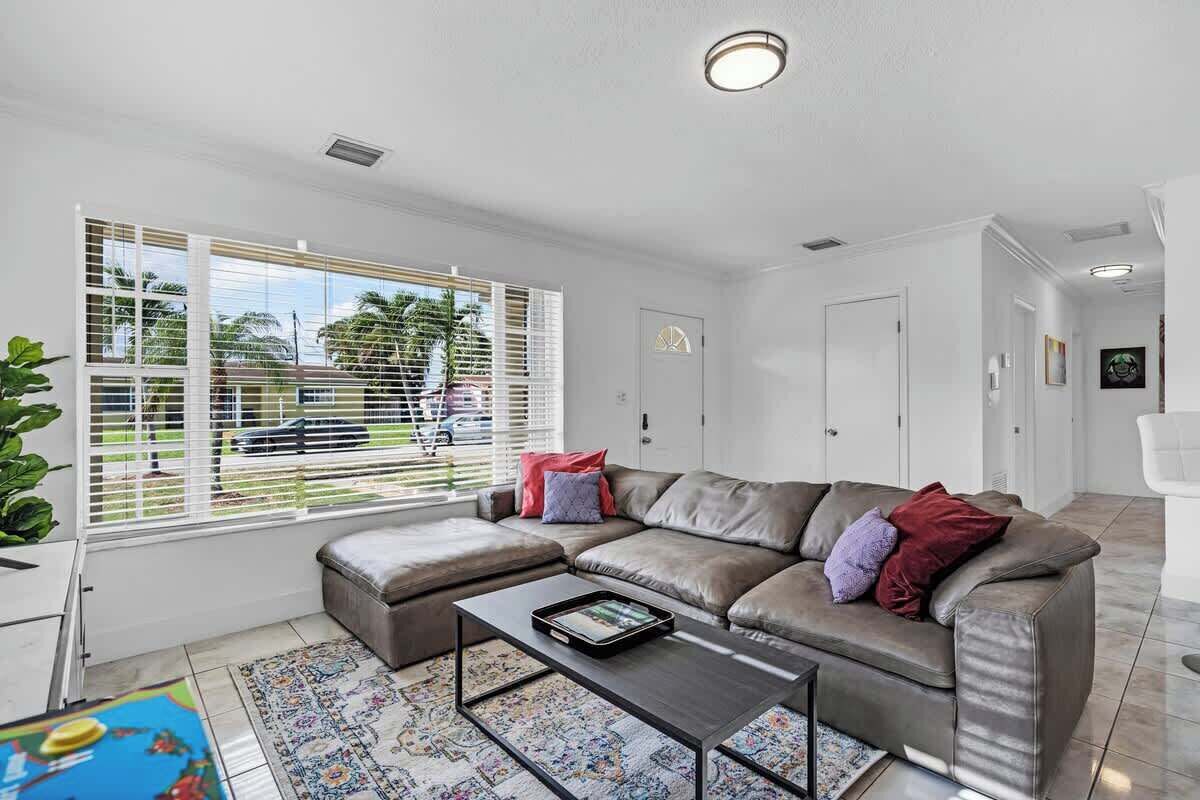 A modern living room with a sectional sofa, a coffee table, and a large window with blinds.