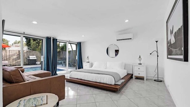 Um quarto moderno com uma cama grande, um sofá, uma mesinha e um abajur.