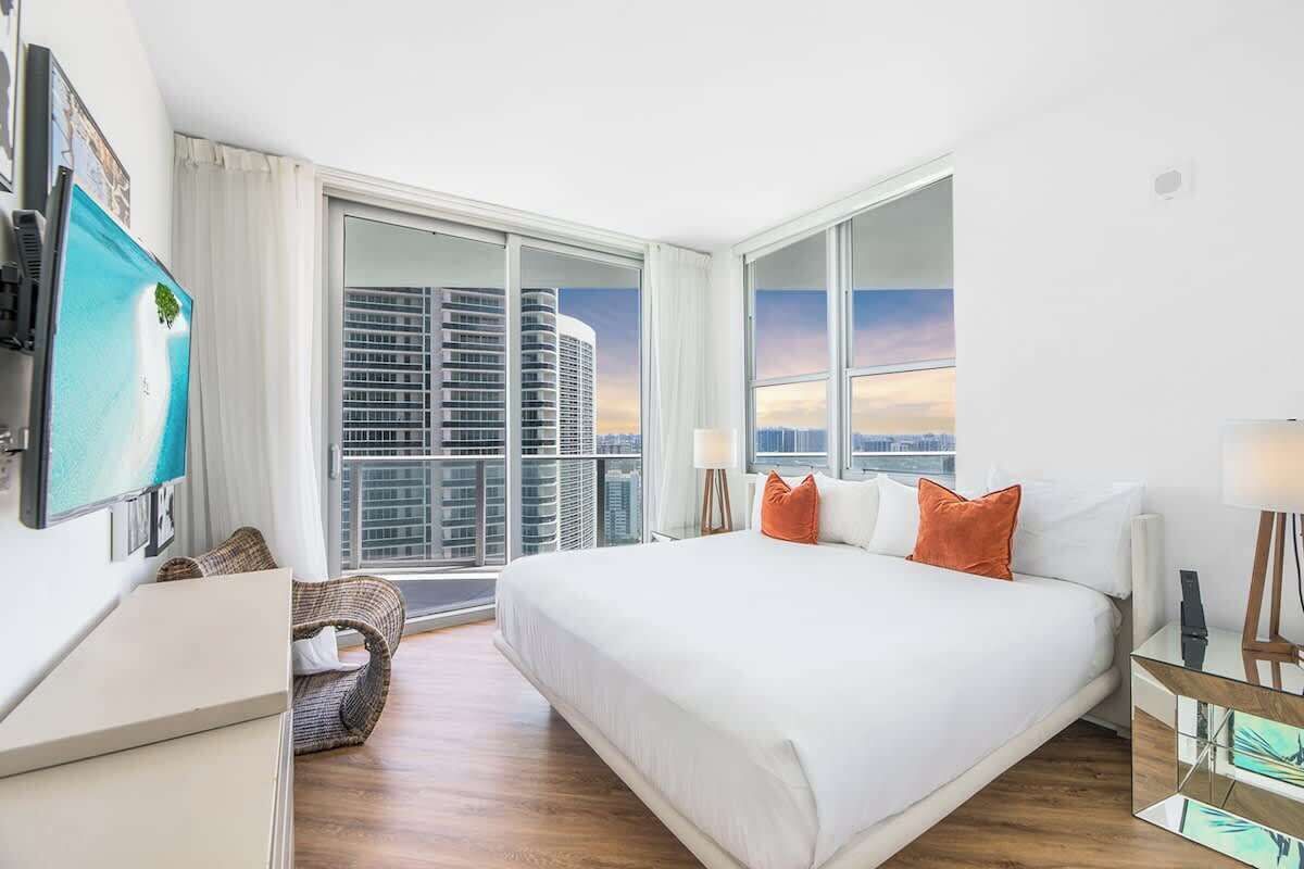 A hotel room with a large bed, a desk, a chair, and a TV.