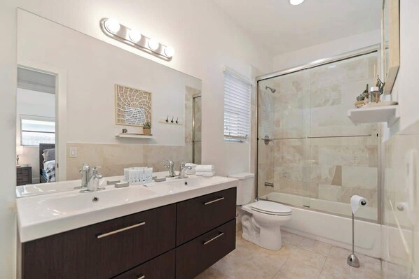 A modern bathroom with a double sink vanity, a toilet, and a glass-enclosed shower. - Lux Miami Villa Heated Pool 10 min to Beach (North Miami Beach)