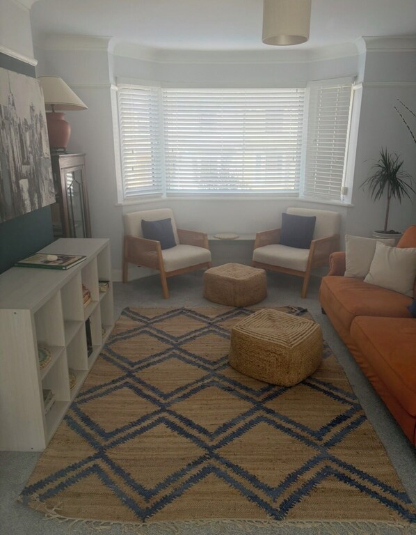 A living room with a patterned rug, two armchairs, a sofa, and a television on a white console. - Stunning Margate seaside retreat (Margate)
