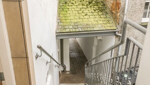 A staircase with metal railings, a tiled roof, and a brick wall. - Hay Loft (Anstruther)