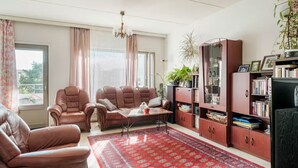 A living room with leather sofas, a coffee table, a red patterned rug, a bookshelf, and a plant. - Bright 2-bedroom apartment with heating system in beautiful Espoo (Espoo)