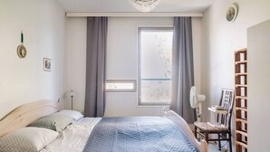A bedroom with a bed, a window with curtains, a bedside table with a lamp, and a wooden chair. - Bright 2-bedroom apartment with heating system in beautiful Espoo (Espoo)