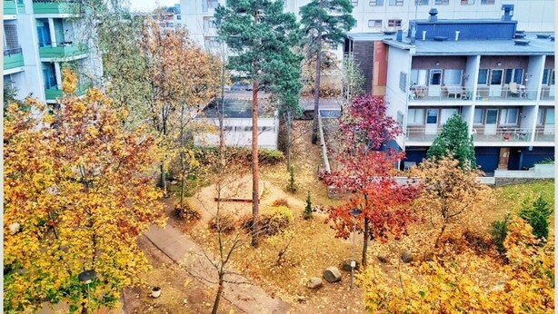 A residential area with multi-story buildings, trees with autumn foliage, and a paved pathway. - Bright 2-bedroom apartment with heating system in beautiful Espoo (Espoo)