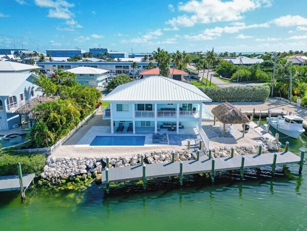 A coastal property with a large pool, a dock, and a view of the ocean. - Dockside Paradise | Brand New, Large Dock, Private Pool, Tiki Hut, Walk to Sombrero Beach (Marathon)